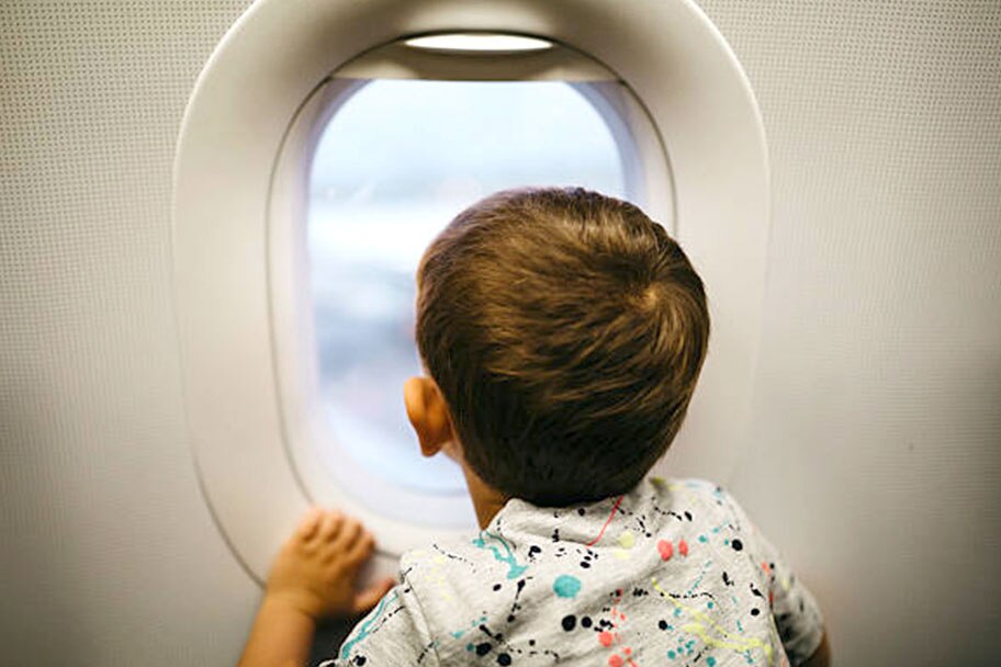 Toddler boy looking outside of the airplane window
