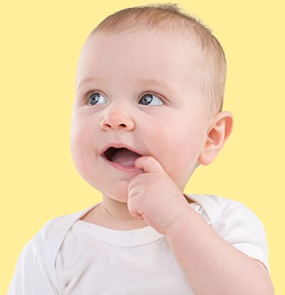 A baby holds his finger up to his mouth.