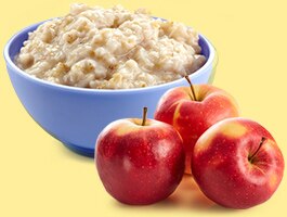 Three red apples beside a bowl of oatmeal.