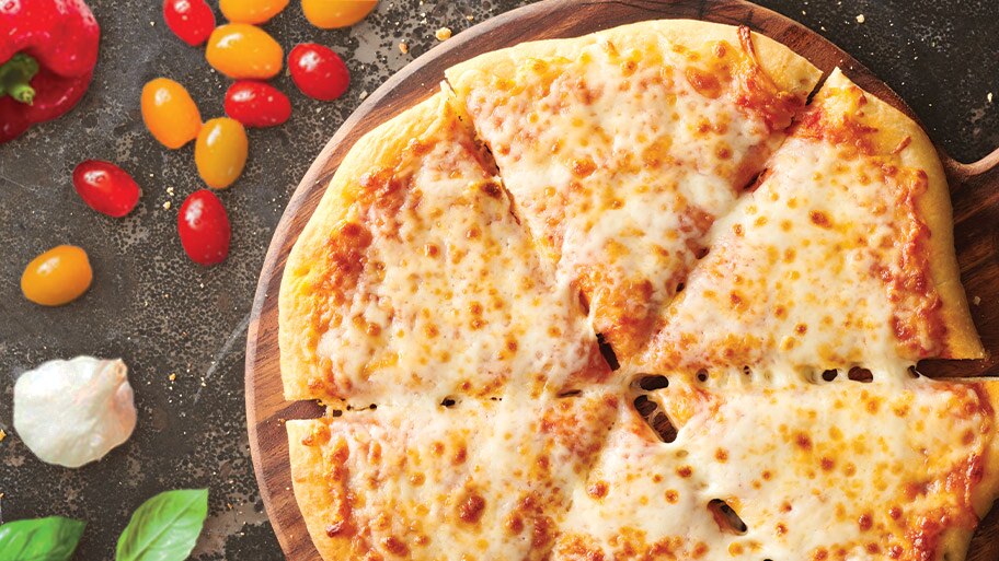A DiGiorno pizza on a wooden tray near cherry tomatoes, a red pepper and basil on a granite counter.