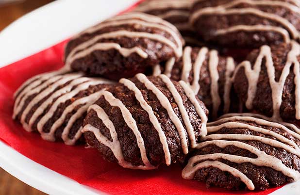 Galletas de chocolate con baño blanco sobre un plato y una servilleta roja.