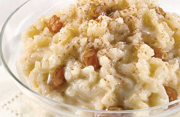 Un plato transparente de arroz con leche y pasas doradas. 