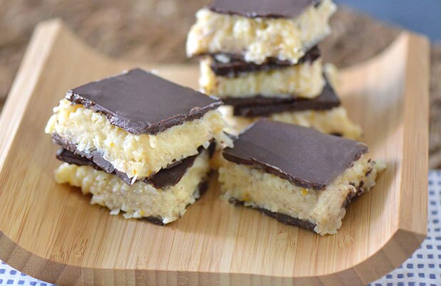 Barras de chocolate de coco en una bandeja de servir de madera curvada.