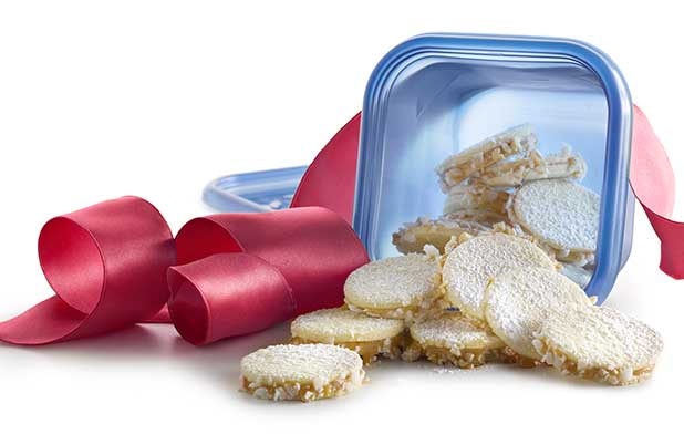 Galletas tipo sándwich se derraman de un recipiente de plástico resellable con una gran cinta roja.