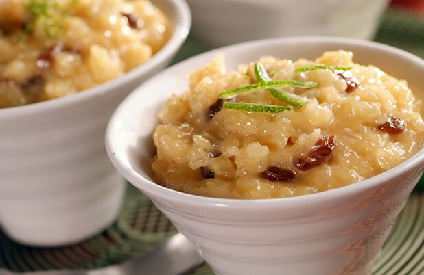 Platitos blancos llenos de arroz con leche con gajos de limón y pasas por encima.