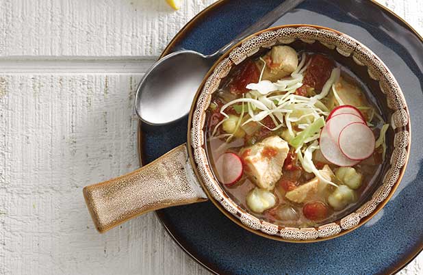 Un cuenco de cerámica de pozole de pollo con repollo y rábano.