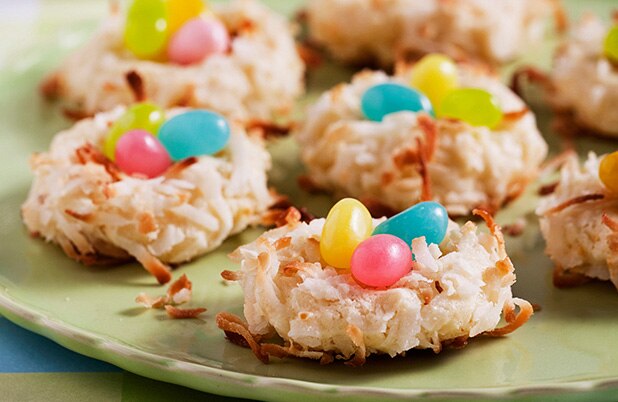 Macarrones de coco cubiertos con huevitos de dulce sobre un plato color verde.