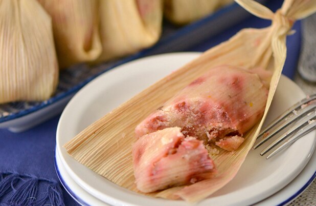 Un tamal de guayaba y pacanas abierto sobre un plato blanco con un tenedor.
