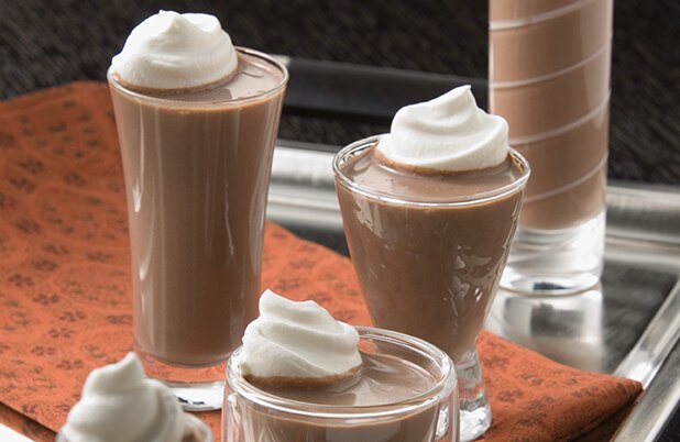 Vasos de chupito altos llenos de chupitos de moca de menta caliente cubiertos con crema batida.