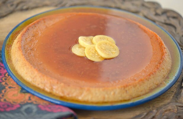 Un flan delgado cubierto de rebanadas de guayaba sobre un plato de cerámica.