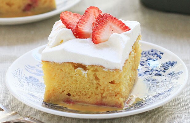 Una porción de pastel de tres leches con fresas por encima.