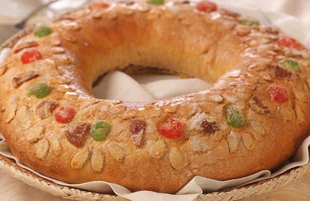 Una rosca de Reyes adornada con fruta roja y verde.