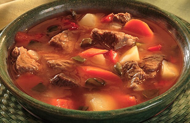 Un tazón de cerámica color verde lleno de estofado de carne y verduras.
