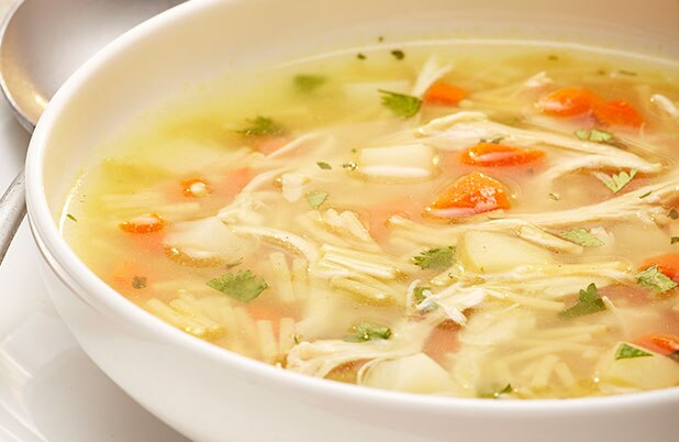 Un tazón de sopa de verduras con fideos delgados y cilantro.