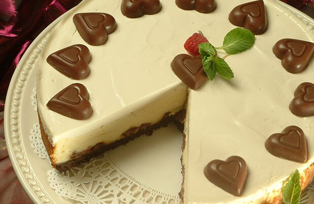 Una tarta de queso con caramelos en forma de corazón como guarnición en un plato decorativo.