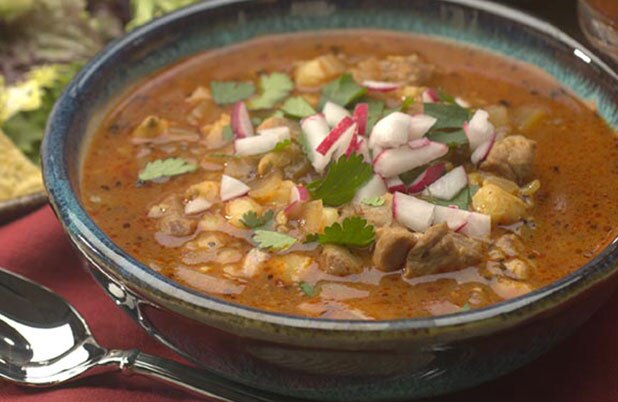 Un tazón de cerámica de estofado adornado con rábano y cilantro.