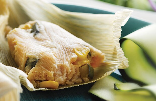 Un tamal abierto relleno con maíz y calabacín.