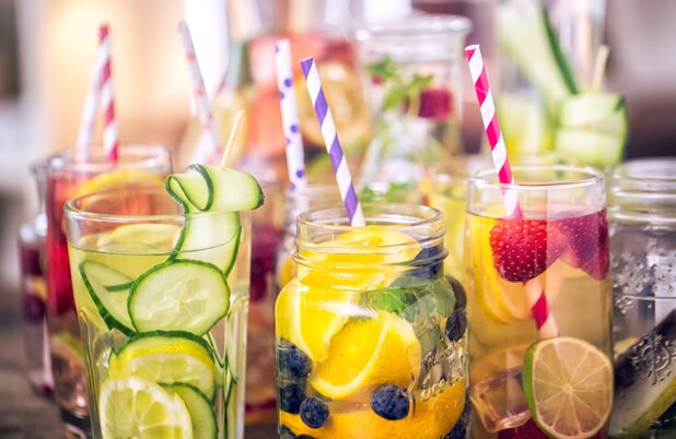 Varias jarras y vasos llenos de fruta fresca, hielo y popotes.