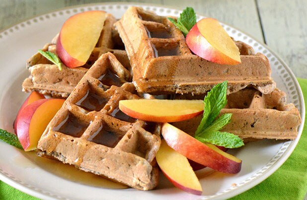 Un plato con waffles, almíbar y rodajas de manzana aderezadas con menta.