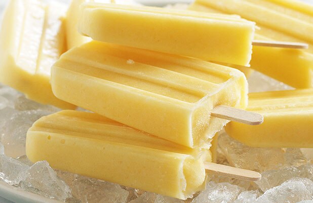 Paletas de helado de coco y mango sobre hielo picado.