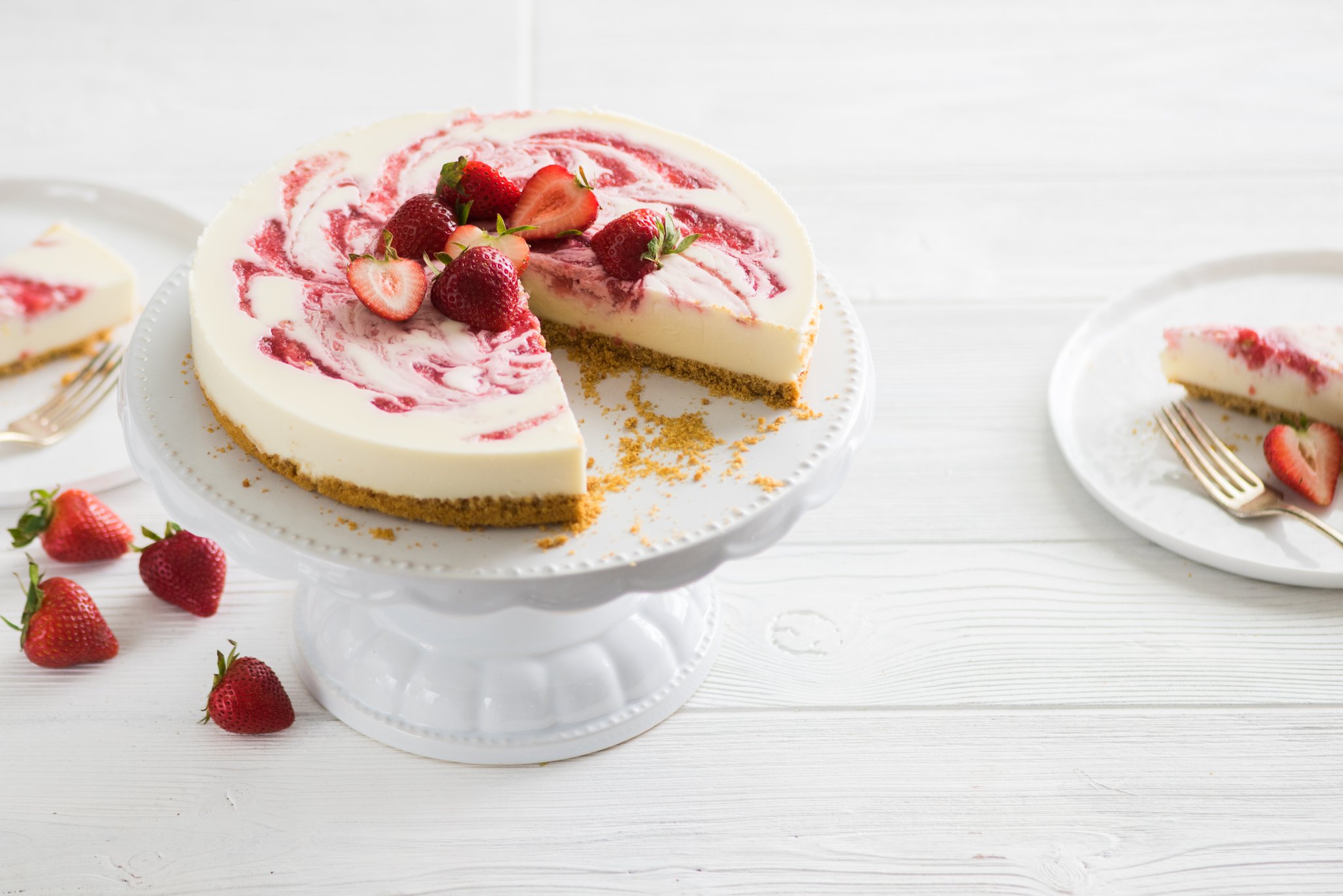 A cheesecake with heart shaped candies as garnish on a decorative platter.