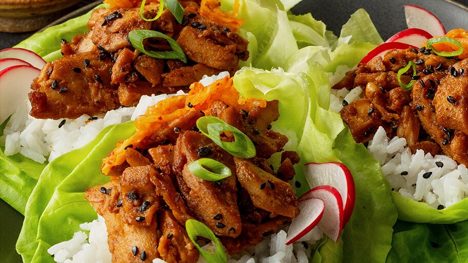 Wraps coreanos de BBQ y lechuga con una guarnición de cebolletas, semillas de girasol y rábano rebanado.