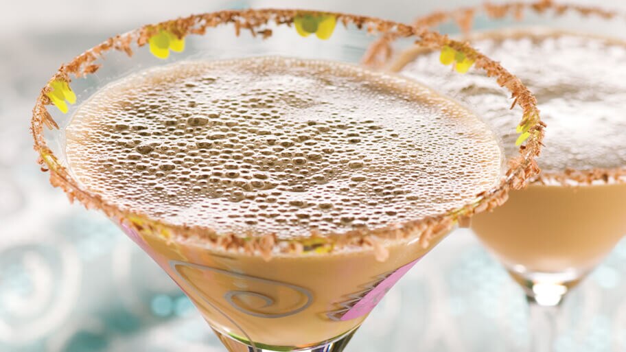 Primer plano de dos espresso martinis en copas de martini decoradas con el borde con chocolate en polvo.