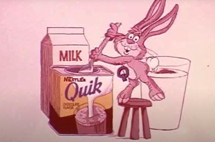 A vintage illustration of a bunny spooning Nestlé Quik into a glass of milk. 