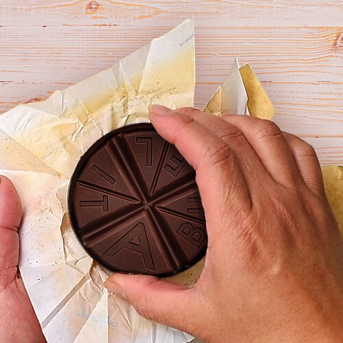 A hand grabs an ABUELITA tablet from the wrapper.