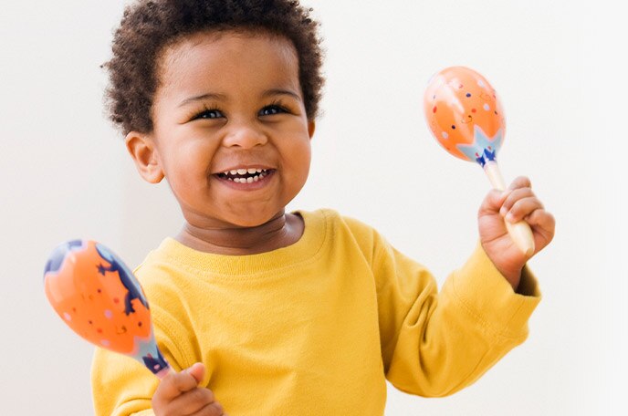 A young boy plays with toy maracas.