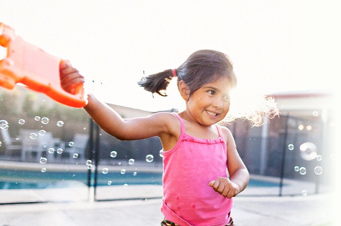 A young girl twirls and plays with bubbles.