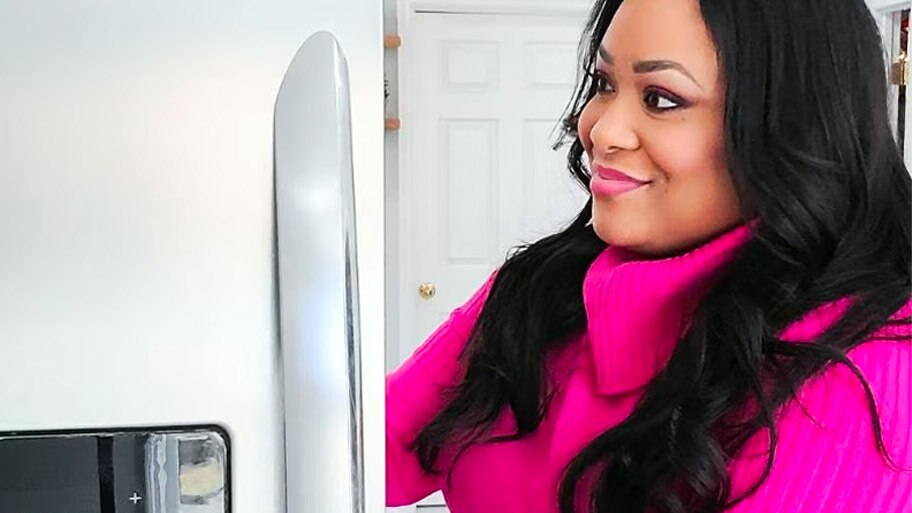 Registered Dietician Andrea Mathis wears a bright pink sweater and looks into her fridge.