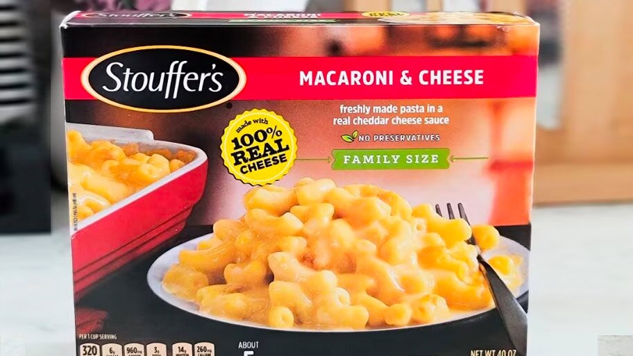 A box of Stouffer’s family size Macaroni & Cheese on a kitchen counter in front of a plant and knife block.