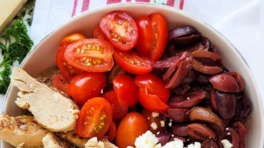 A bowl of chicken, feta cheese, kalamata olives and cherry tomatoes.