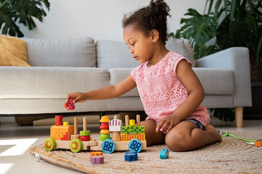Toddler playing with blocks on the ground infront of a couch.