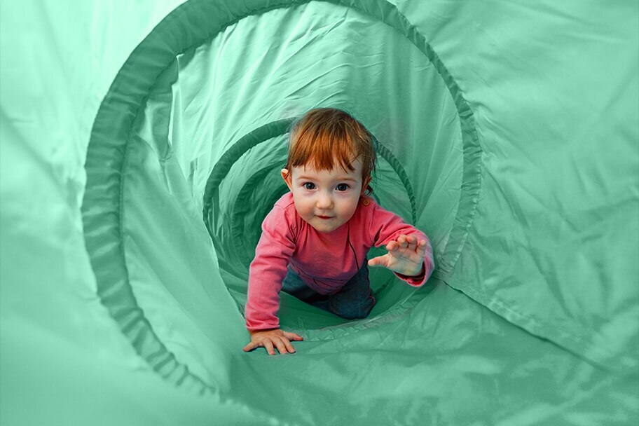 child crawling in a green fabric play tube.