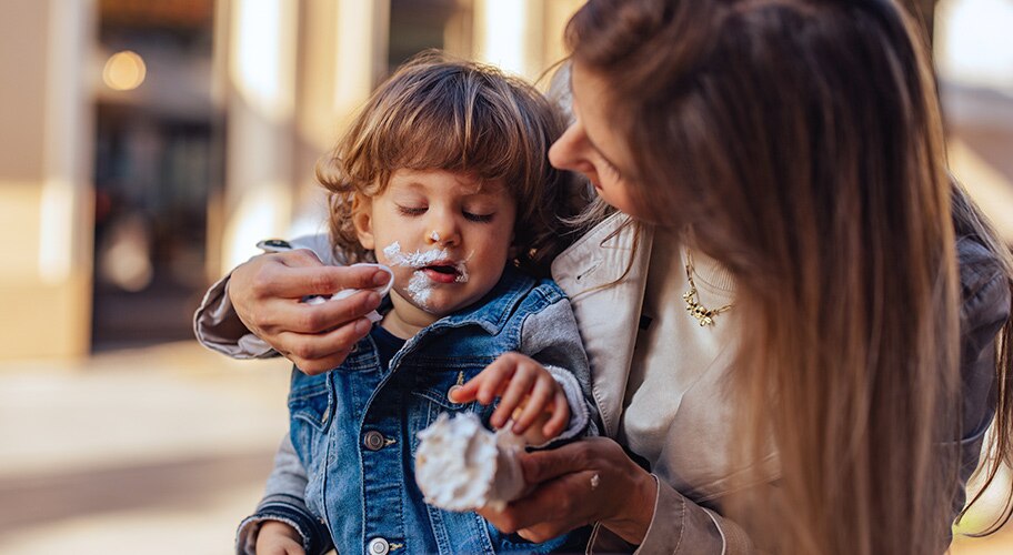 Mother cleaning up ice cream from a childs face.