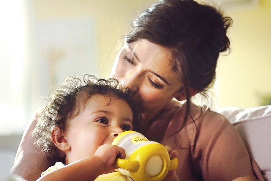 Mother holding child with a Nido bottle.
