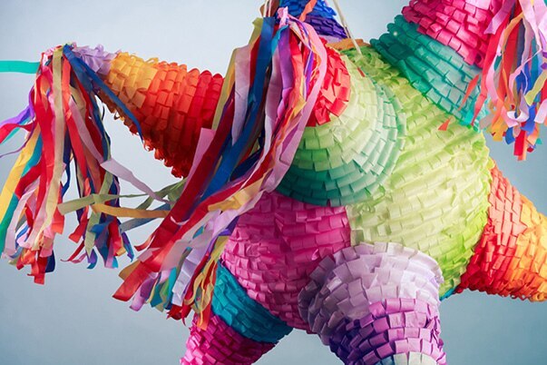 A classic nine-cornered piñata is balanced in front of a blue wall.