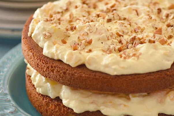 Two layer cake with mango whipped frosting between the layers and on top.