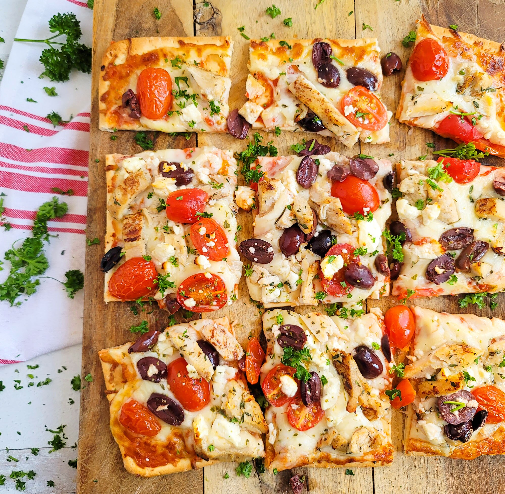 A DiGiorno Four Cheese Thin Crust pizza topped with chicken, feta cheese, kalamata olives and cherry tomatoes.