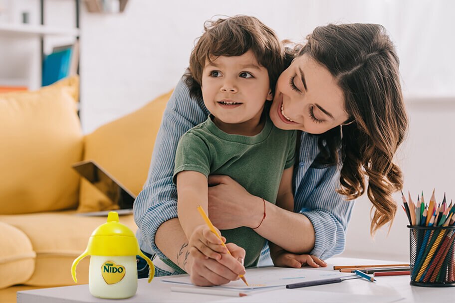 Child Drawing with Mom in a living room with a Nido Bottle on the table.