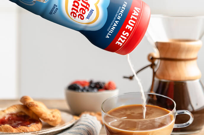 Polvo vaciado de una lata a una taza de café cerca de una cafetera que sirve, un plato de galletas y un tazón de fruta.