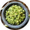 Guacamole en un tazón de piedra sobre una mesa de madera.