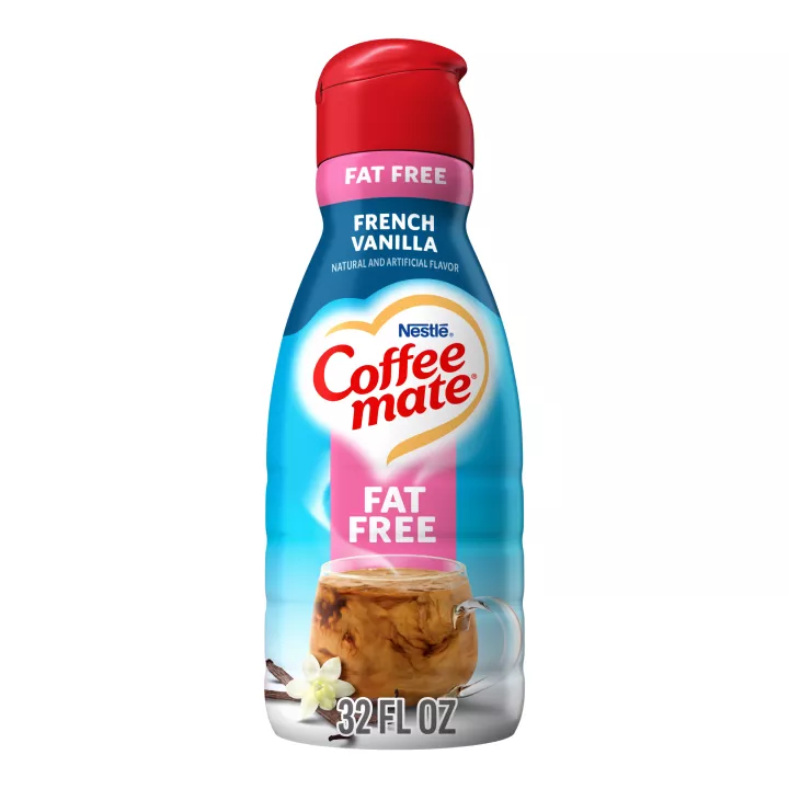 Una botella de creamer líquido French Vanilla con una tapa roja y una etiqueta rosada que dice "Sin grasa" encima de una taza y vainas de vainilla.