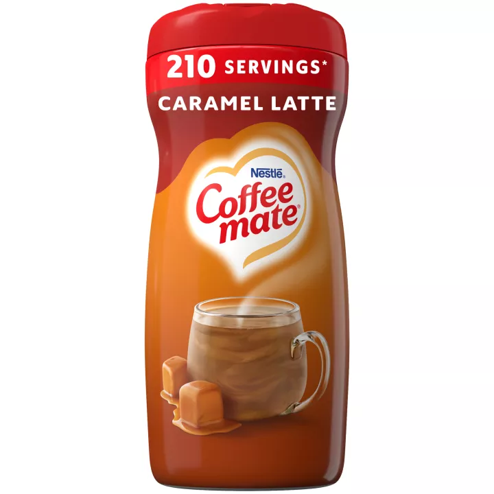 A brown canister of Coffee mate Caramel Latte Creamer with a red label above a mug of coffee with caramel drizzle.