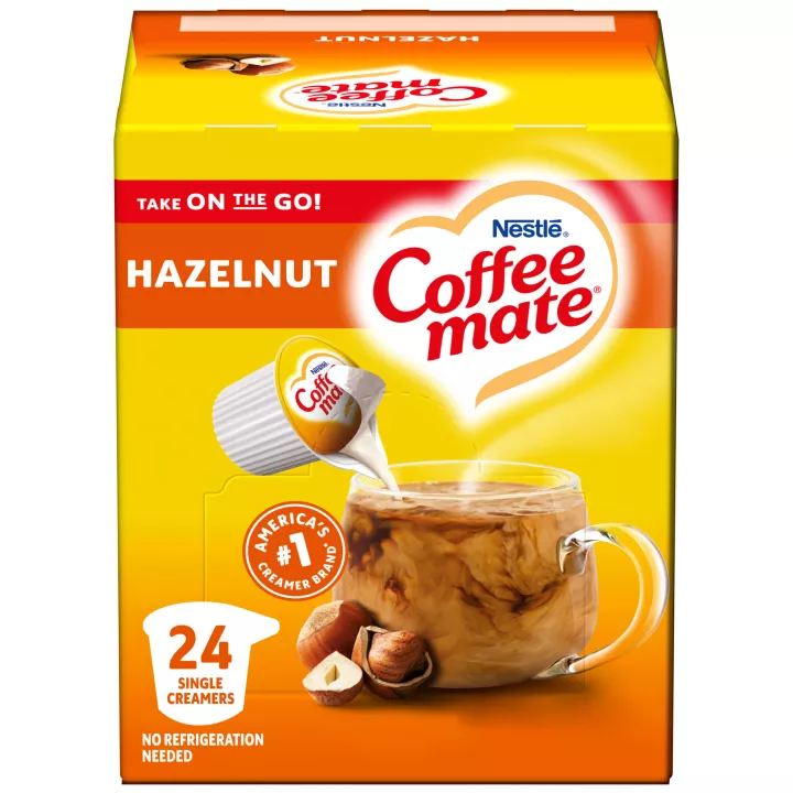 A box of single serve hazelnut Coffee mate creamer featuring an orange label, coffee mug, hazelnuts and the Coffee mate logo.