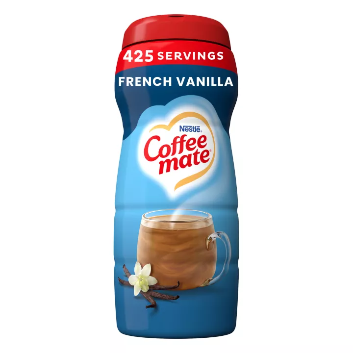 Una lata azul de creamer en polvo Coffee mate French Vanilla con una gorra roja encima de una taza de café y vainas de vainilla.