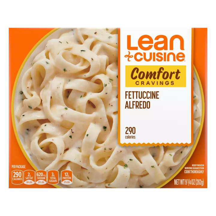 A box of Fettuccini Alfredo with a Comfort Cravings label near a bowl of fettuccini covered with Alfredo sauce.