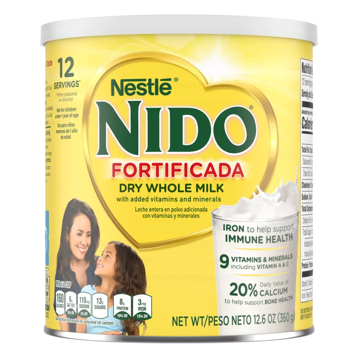 A canister of Nido Fortificada with a yellow label, white lid and gold heart above a glass of milk pouring.